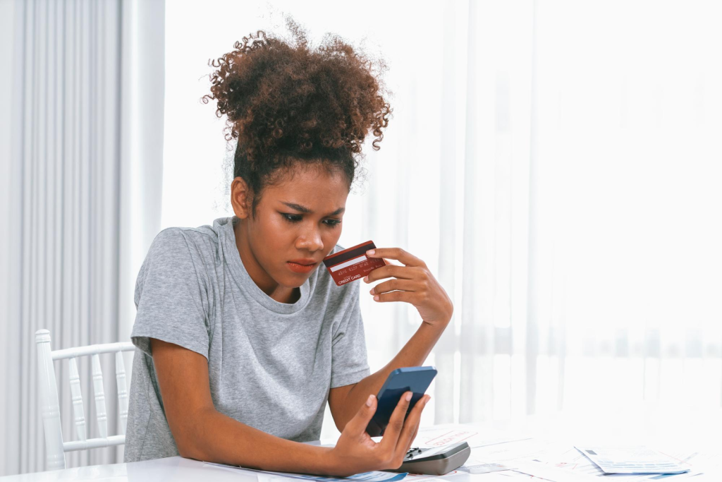 A curious lady with a credit card in one hand and phone in the other wondering what a 609 credit score is good or bad