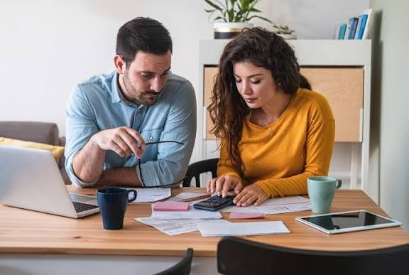 A man and woman with curly hair looking into their credit report and wondering "Can I hire a lawyer to fix my credit?"